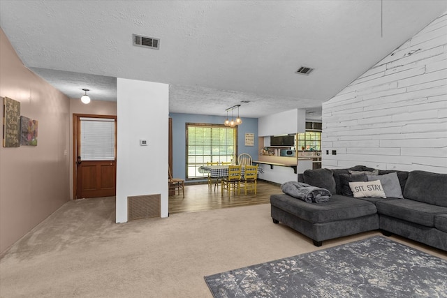 carpeted living room featuring wood walls, a textured ceiling, and a chandelier