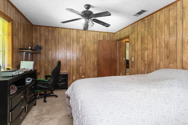 bedroom with light carpet, a textured ceiling, ceiling fan, and wood walls