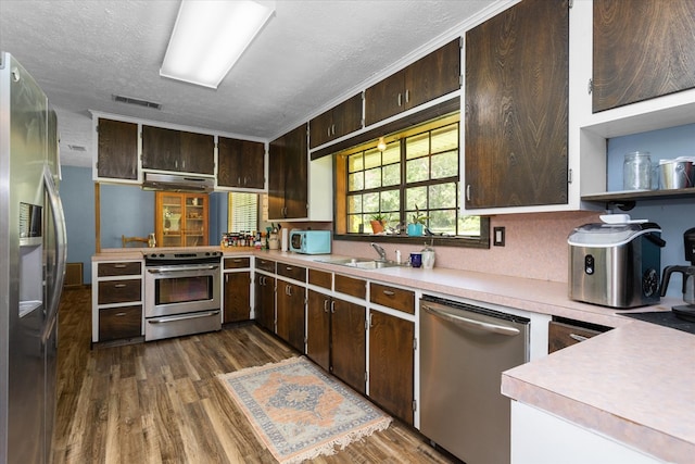 kitchen with sink, a textured ceiling, dark brown cabinets, dark hardwood / wood-style flooring, and stainless steel appliances