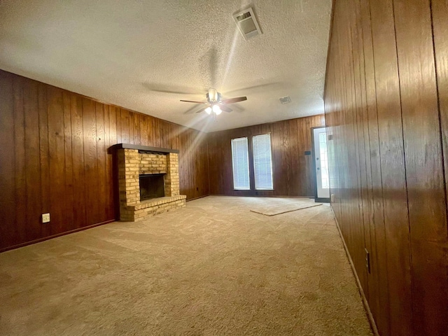 unfurnished living room featuring ceiling fan, light colored carpet, a fireplace, and wooden walls