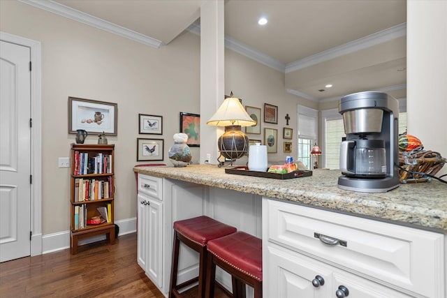 kitchen with crown molding, white cabinetry, dark hardwood / wood-style flooring, and light stone counters