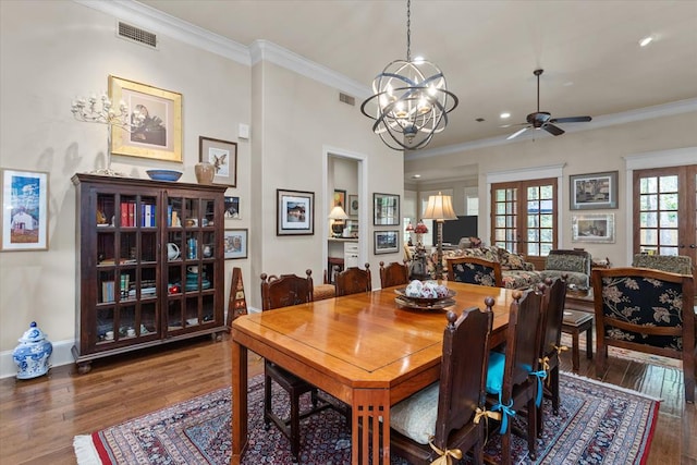 dining space with ceiling fan with notable chandelier, dark hardwood / wood-style flooring, ornamental molding, and french doors