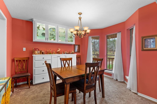 carpeted dining area featuring a wealth of natural light, a textured ceiling, and an inviting chandelier