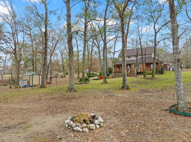 view of yard featuring a storage unit, a deck, and a fire pit