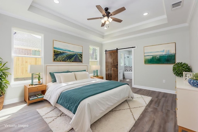 bedroom with ornamental molding, a tray ceiling, visible vents, and a barn door