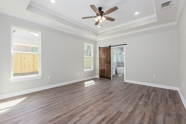 unfurnished bedroom featuring a raised ceiling, visible vents, baseboards, and a barn door