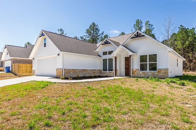 modern inspired farmhouse with a shingled roof, stone siding, driveway, and a front lawn