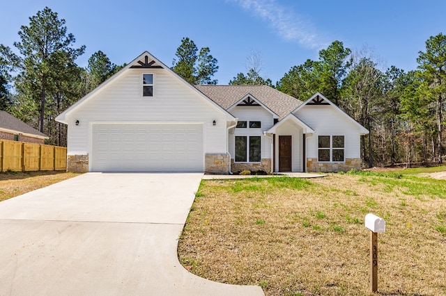 modern inspired farmhouse with a garage, fence, concrete driveway, stone siding, and a front yard