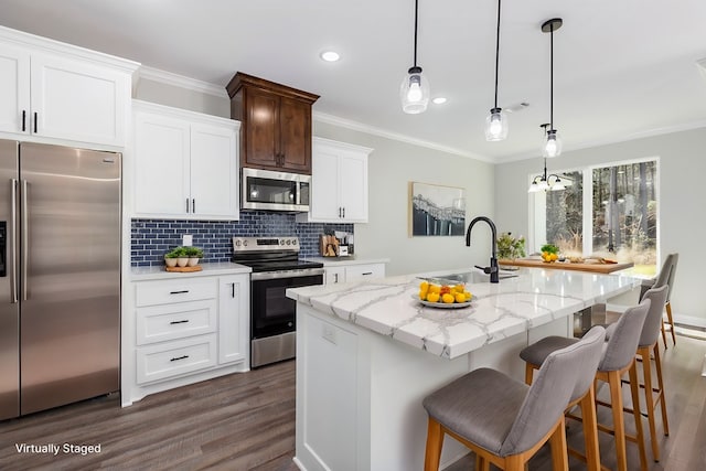 kitchen with appliances with stainless steel finishes, dark wood-type flooring, a sink, and ornamental molding