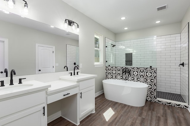 bathroom featuring a walk in shower, wood finished floors, a sink, visible vents, and double vanity