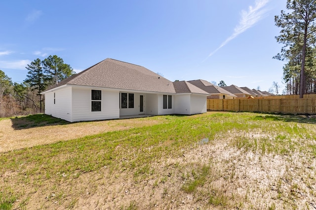 back of property featuring a yard, roof with shingles, and fence