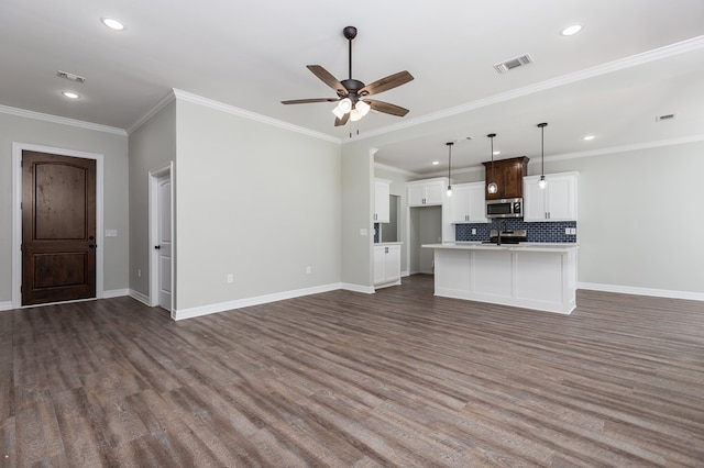 unfurnished living room featuring baseboards, visible vents, ceiling fan, ornamental molding, and wood finished floors