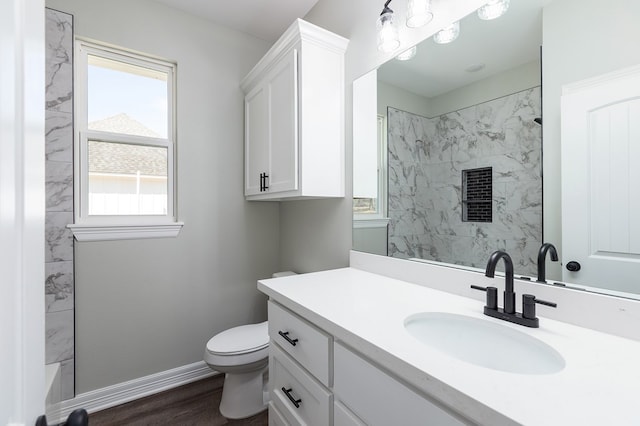 bathroom with toilet, a shower, vanity, and baseboards