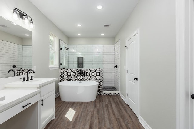 full bathroom with wood finished floors, visible vents, vanity, a soaking tub, and walk in shower