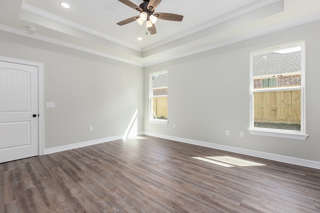 unfurnished room with ornamental molding, a tray ceiling, baseboards, and wood finished floors