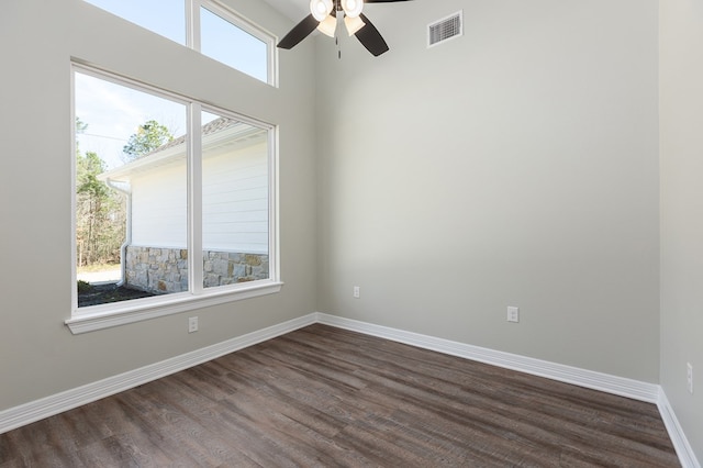 spare room with ceiling fan, dark wood-style flooring, visible vents, and baseboards