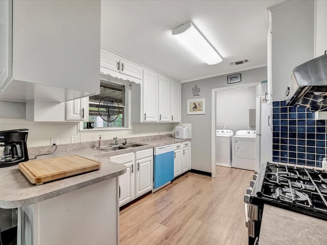 kitchen featuring dishwashing machine, washer and dryer, gas range, and white cabinetry