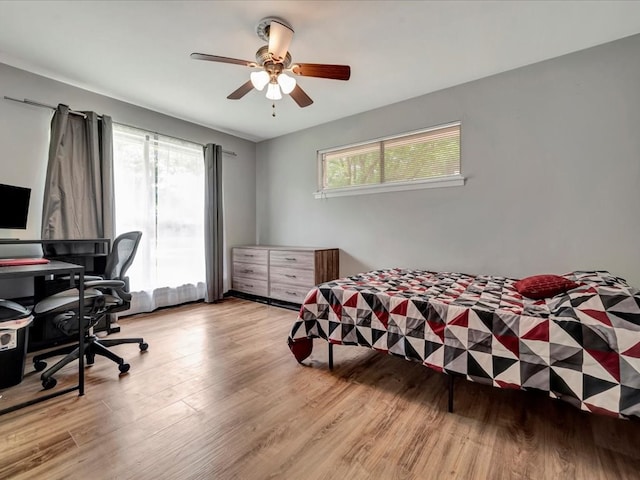 bedroom with ceiling fan, multiple windows, and light hardwood / wood-style flooring