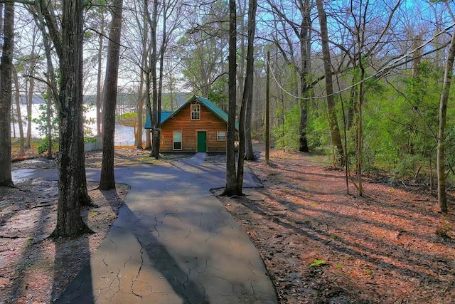 view of front of house with aphalt driveway and a wooded view