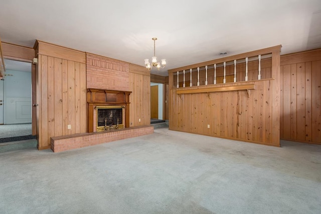 unfurnished living room with wood walls, carpet floors, and an inviting chandelier