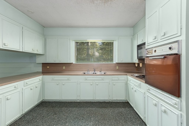 kitchen with white cabinetry, sink, black appliances, and a textured ceiling