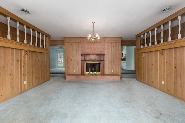 unfurnished living room featuring a large fireplace, carpet floors, and a notable chandelier