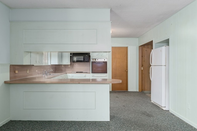 kitchen featuring kitchen peninsula, stainless steel oven, a textured ceiling, white refrigerator, and white cabinetry