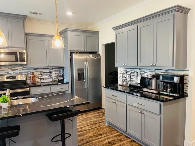 kitchen featuring stainless steel appliances, backsplash, dark stone countertops, crown molding, and pendant lighting