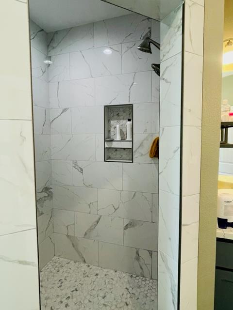 bathroom with a tile shower and vanity