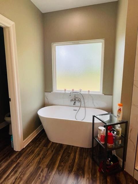 bathroom featuring a washtub, hardwood / wood-style floors, and toilet