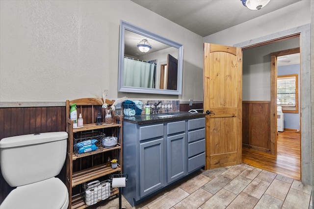 bathroom featuring hardwood / wood-style floors, vanity, toilet, and wooden walls