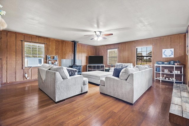 living room featuring a wood stove, dark wood-type flooring, a healthy amount of sunlight, and a textured ceiling