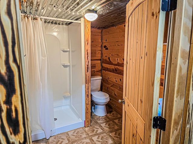 full bathroom featuring wooden ceiling, toilet, a stall shower, and wood walls