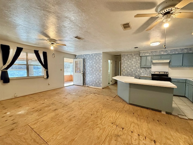 kitchen with ceiling fan, kitchen peninsula, black range with electric cooktop, and a textured ceiling