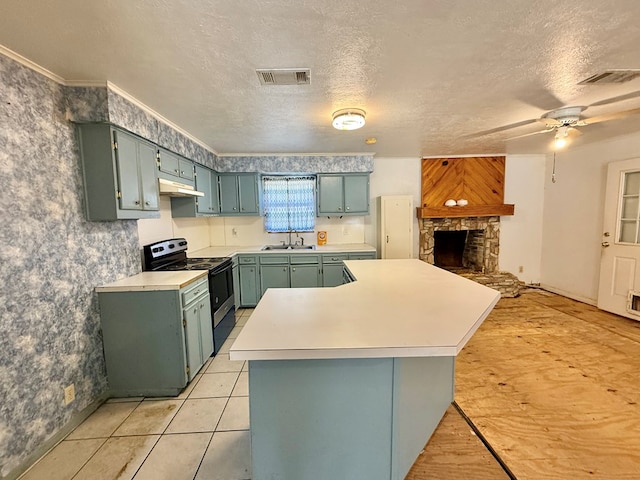 kitchen featuring sink, ceiling fan, electric range, a textured ceiling, and a stone fireplace