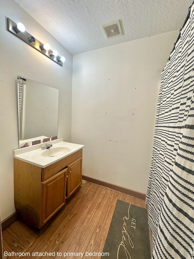 677 County Road 105, San Augustine, TX 75972 - bathroom featuring wood finished floors, vanity, a textured ceiling, baseboards, and a shower with curtain