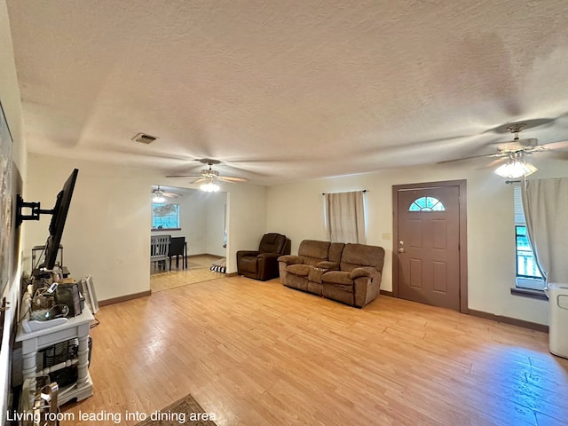 677 County Road 105, San Augustine, TX 75972 - living room featuring a ceiling fan, light wood-type flooring, a textured ceiling, and baseboards