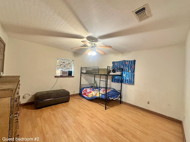 677 County Road 105, San Augustine, TX 75972 - bedroom featuring wood finished floors, baseboards, cooling unit, a textured ceiling, and ceiling fan