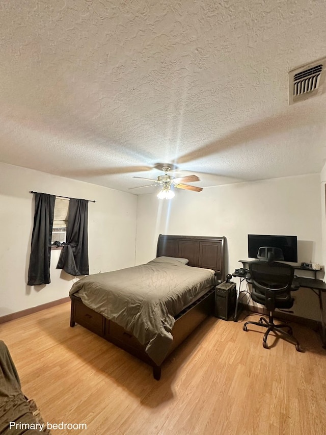 677 County Road 105, San Augustine, TX 75972 - bedroom with light wood-style flooring, a textured ceiling, a ceiling fan, and baseboards