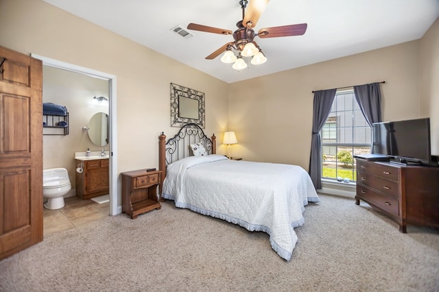 bedroom with light colored carpet, ensuite bath, a ceiling fan, and visible vents
