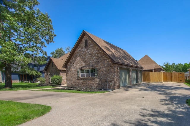 view of side of property with concrete driveway, brick siding, fence, and a garage