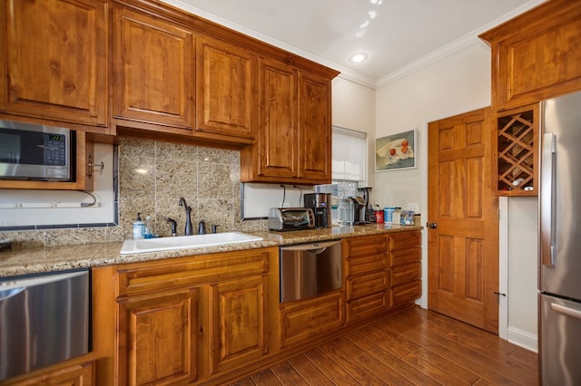 kitchen with stainless steel appliances, ornamental molding, a sink, decorative backsplash, and brown cabinetry