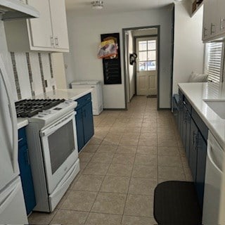 kitchen with blue cabinets, white cabinets, light tile patterned flooring, and white appliances