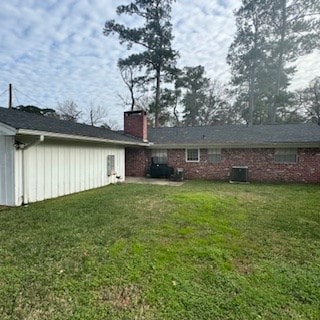 rear view of property featuring central AC unit and a lawn