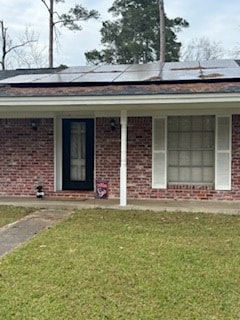 ranch-style home with a front yard and solar panels