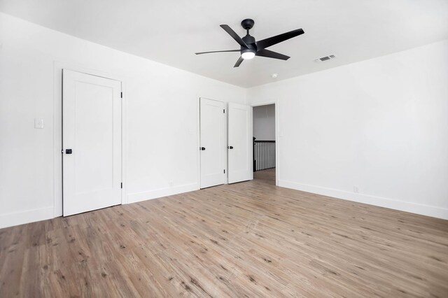 508 Jefferson Ave, Lufkin, TX 74904 - unfurnished bedroom featuring light wood-style floors, baseboards, multiple closets, and a ceiling fan