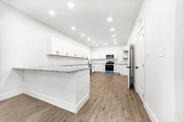 508 Jefferson Ave, Lufkin, TX 74904 - kitchen with stainless steel appliances, a peninsula, light stone counters, recessed lighting, and light wood-style flooring