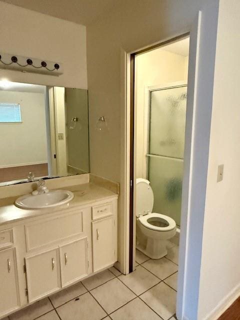 bathroom with tile patterned flooring, vanity, a shower with door, and toilet