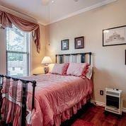 208 E Livingston St, San Augustine, TX 75972 - bedroom with ornamental molding, baseboards, heating unit, wood finished floors, and ceiling fan