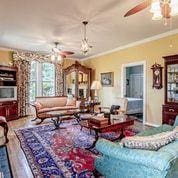 208 E Livingston St, San Augustine, TX 75972 - living room featuring a ceiling fan, crown molding, and wood finished floors